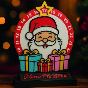 May include: A Christmas-themed decoration featuring a Santa Claus design with a red hat and white beard. The decoration includes a countdown calendar with numbers and the text "Merry Christmas". There are also three gift boxes in blue, pink, and red.