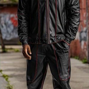 May include: Black tracksuit with red trim. The jacket has a zip-up front and a hood. The pants have a relaxed fit. The outfit is paired with silver and white sneakers. The person is standing on a sidewalk.