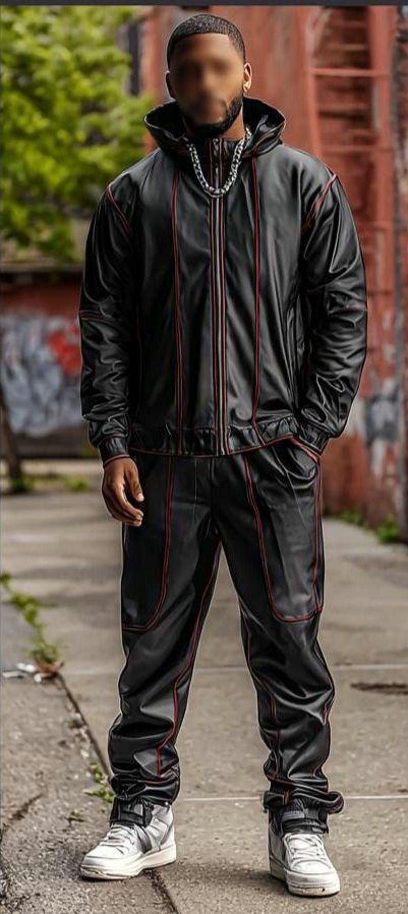 May include: Black tracksuit with red trim. The jacket has a zip-up front and a hood. The pants have a relaxed fit. The outfit is paired with silver and white sneakers. The person is standing on a sidewalk.