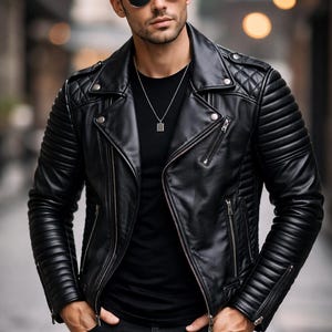 May include: A black leather jacket with a quilted shoulder design and ribbed sleeves. The jacket has a zipper closure and is paired with a black t-shirt and black jeans. The person is wearing sunglasses and a silver necklace.