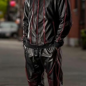 May include: Black tracksuit with red trim. The jacket has a zip-up front and the pants have a drawstring. The outfit is paired with white and red sneakers. The person is standing on a street.
