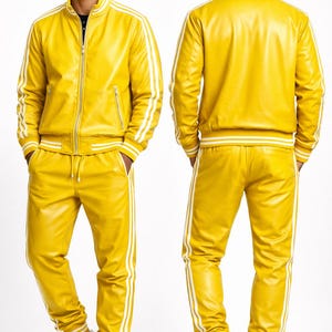 Puede incluir: Ch&aacute;ndal de cuero amarillo con rayas blancas en las mangas de la chaqueta y las perneras del pantal&oacute;n. La chaqueta tiene cierre de cremallera y el pantal&oacute;n, cord&oacute;n. Se completa con zapatillas blancas.