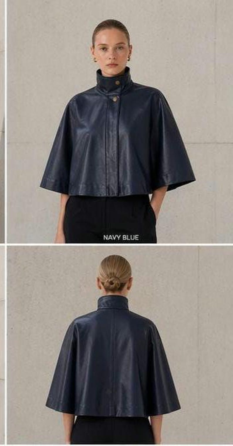 May include: Navy blue leather cape jacket with a high collar and button closure. The jacket has a cropped length and short sleeves. The text "NAVY BLUE" is visible in the image.
