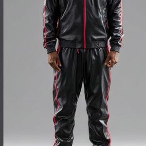 May include: Black tracksuit with red accents. The jacket has a high collar and a red zipper. Red stripes run down the sides of the jacket and pants. The matching pants have a drawstring waist. The outfit is completed with red and white sneakers.