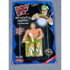 May include: A B.A. Billy Gunn action figure in its original packaging. The figure is a muscular man with blonde hair, wearing green shorts and white boots. The packaging features the WWF logo and the text "Bendable, Poseable, Collectable".