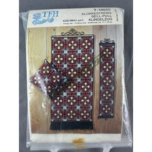 May include: A packaged cross-stitch kit featuring a red, black, and white floral design. The kit includes a bell pull, a pillow, and a smaller decorative piece. The package has text in multiple languages, including "BELL-PULL" and "KLINGELZUG". The finished size is approximately 6.7 x 30.7 inches.