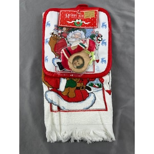 Könnte beinhalten: Ein weihnachtliches Küchenset mit einem Topflappen und einem Handtuch. Der Topflappen ist rot mit weißem Rand und einem Weihnachtsmann-Motiv. Das Handtuch ist weiß mit rotem Rand und einem Weihnachtsmann-Motiv. Das Set ist neu mit Etiketten.