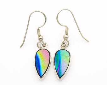 May include: A pair of silver-toned teardrop earrings. Each earring features a colorful, iridescent, teardrop-shaped stone set in a silver bezel. The stones display hues of pink, blue, green, and yellow. The earrings hang from silver fish hook ear wires.
