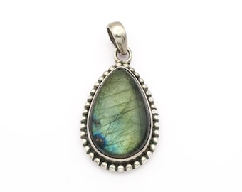 May include: A teardrop-shaped pendant with a silver-colored setting. The pendant features a green and blue iridescent gemstone, surrounded by a beaded border. The bail is also silver-colored.