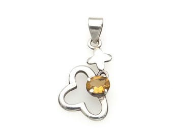 May include: A silver pendant featuring an open, four-petaled flower shape with a small, oval-cut yellow citrine gemstone set in the center. The pendant includes a silver bail at the top for attachment to a chain, showcasing a polished metallic finish.