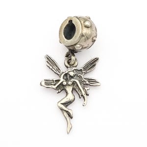 May include: A silver-toned charm featuring a fairy design. The charm has a detailed fairy figure with outstretched wings and a cylindrical top with a hole for stringing. The fairy is in a graceful pose.