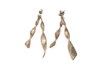 May include: A pair of silver-toned drop earrings featuring a twisted, spiral design. Each earring consists of two elongated, textured metal ribbons that converge at the top post, creating a dynamic, flowing shape with a metallic, weathered finish.