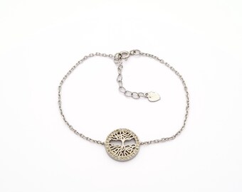 May include: Silver-toned bracelet featuring a circular pendant with a tree of life design. The pendant is embellished with small, clear stones. The bracelet has a delicate chain and an adjustable clasp.