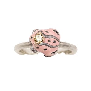 Op de afbeelding: Zilveren ring met een roze lieveheersbeestje-ontwerp met zwarte stippen en een kleine, ronde, gele edelsteen in het midden. Het lichaam van het lieveheersbeestje is lichtroze.