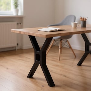 May include: A rectangular wooden desk with a light brown tabletop and black metal X-shaped legs. A notebook, a white mug, and a pencil holder are on the desk. The desk is in a room with a wooden floor and a gray chair.