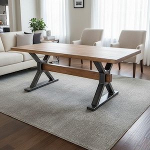 May include: A rectangular dining table with a natural light brown wood grain top and a dark gray metal base. The base features two X-shaped supports connected by a horizontal wooden beam that runs between the two legs, providing structural stability.