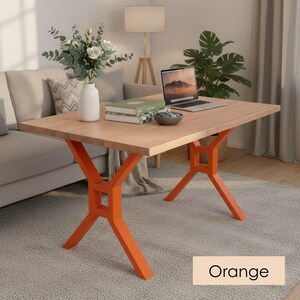 May include: A rectangular wooden table with a light brown surface and bright orange legs. The legs have an X-shaped design. The table is in a living room setting, with a laptop, books, and a vase of flowers on top. The word "Orange" is in the image.