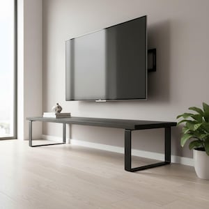 Puede incluir: Un mueble multimedia largo y bajo de madera negra con una superficie rectangular plana y dos patas robustas de metal negro con marco abierto. El mueble está colocado horizontalmente contra una pared, directamente debajo de un televisor de pantalla plana.