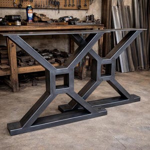 以下が含まれることがあります： 幾何学的なデザインの、2つの生の鉄鋼製テーブルベース。ベースは長方形の上面と、正方形で合わさる角度の付いたサポートを備えています。テーブルトップを支えるように設計されています。