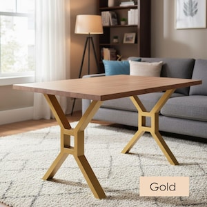 May include: A rectangular wooden table with a light brown surface and gold-coloured metal legs. The legs have an X-shaped design with a square detail in the centre. The word "Gold" is in a beige rectangle at the bottom.