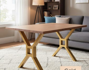 May include: A rectangular wooden table with a light brown surface and gold-colored metal legs. The legs have an X-shaped design with a square detail in the center. The word "Gold" is in a beige rectangle at the bottom.