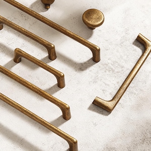 Könnte beinhalten: Eine weiße Keramik-Tasse mit schwarzem Henkel und dem Text "But First, Coffee" in fetter, schwarzer Schrift. Die Tasse steht vor einem verschwommenen Hintergrund, der eine gemütliche Umgebung suggeriert.