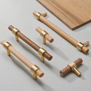 May include: A selection of wooden cabinet handles with brass detailing. Some are light-coloured wood, others are a darker brown. The handles come in various sizes and shapes, suitable for drawers or cabinets.
