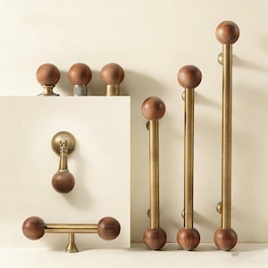 Puede incluir: Una colección de herrajes de madera y latón, que incluye pomos, tiradores y manijas. Los pomos tienen un diseño redondo de madera, mientras que los tiradores combinan madera y latón. Ideal para armarios y puertas.