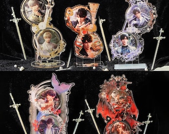 May include: A collection of six decorative acrylic stands featuring portraits of people. Each stand has a unique design with ornate frames, and is accompanied by a small sword. The color palette includes gold, red, and purple accents.