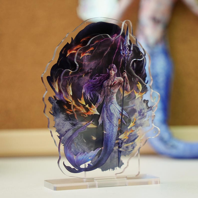 May include: A clear acrylic stand featuring a detailed illustration of a merman with purple hair and a blue tail, holding a trident. The artwork includes fiery orange and purple elements, set against a dark background.