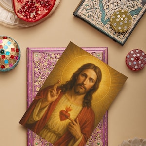 May include: An image featuring a portrait of Jesus Christ, a purple journal, and a teal journal with ornate designs. Also included are decorative round containers, a pomegranate, and a flower.