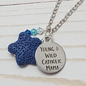 Könnte beinhalten: Silberne Halskette mit Anhänger mit der Aufschrift "Young & Wild Catholic Mama". Die Halskette hat auch einen blauen sternförmigen Anhänger und kleine blaue und klare Perlen.