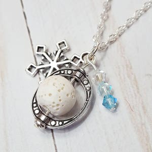 Könnte beinhalten: Eine silberne Halskette mit einem Schneeflocken-Anhänger, einer weißen Lavakugel und blauen Kristall-Akzenten.