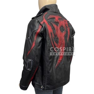 Puede incluir: Chaqueta de cuero negra con detalles rojos y un gran gráfico rojo en la espalda. La chaqueta tiene un estilo motero clásico con cuello de solapa, cremallera asimétrica y bolsillos. La marca "Cospire Creations" es visible.