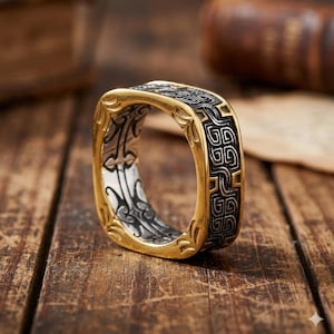 Anillo vikingo nórdico cuadrado: joya con banda celta negra y dorada en relieve.