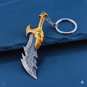 以下が含まれることがあります： 金色の柄と銀色の刃を持つミニチュアの剣を特徴とする、詳細なキーホルダー。柄には複雑なデザインがあり、刃にはユニークなギザギザのエッジがあります。キーホルダーには、鍵を取り付けるための銀色のリングが含まれています。