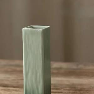 以下が含まれることがあります： テクスチャ加工された表面を持つ正方形の薄い緑色のセラミック花瓶