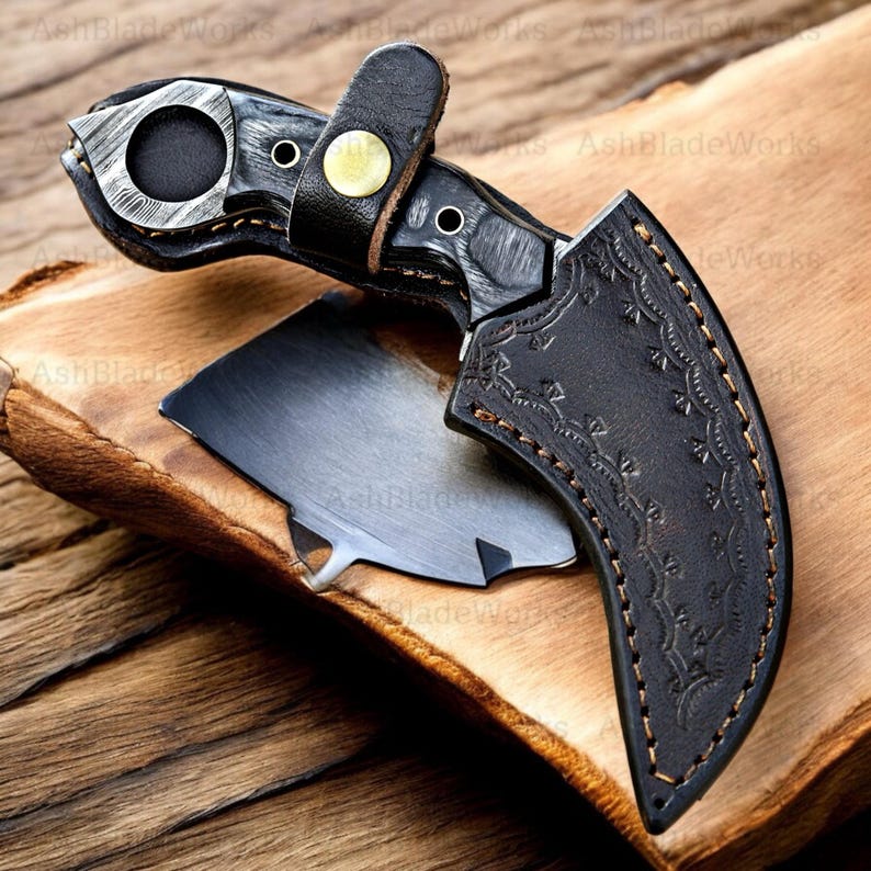 Pu&ograve; includere: Un coltello karambit artigianale con manico nero e lama ricurva. Il coltello &egrave; accompagnato da un fodero in pelle nera con cuciture decorative. L'impugnatura presenta un anello per le dita ed &egrave; fissata con un cinturino in pelle e un bottone color ottone.