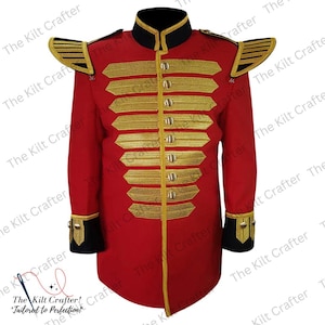 Peut inclure: Veste rouge de style militaire, ornée de garnitures dorées. Elle présente des épaulettes dorées, plusieurs bandes dorées sur la poitrine et des détails dorés sur les poignets. Le col et les poignets sont noirs avec des bordures dorées. Le logo The Kilt Crafter est visible.