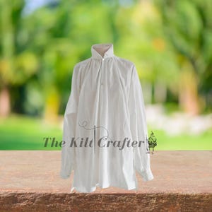 May include: A white long-sleeved shirt with a high collar and button-down front. The shirt has a loose fit and is made of a lightweight fabric. The text "The Kilt Crafter" is printed on the bottom of the shirt.