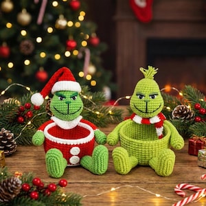 Peut inclure: Deux figurines du Grinch en crochet, l'une avec un bonnet de Père Noël et un costume rouge, l'autre avec une écharpe rouge et blanche. Les figurines vertes avec des détails noirs sont entourées de décorations de Noël.