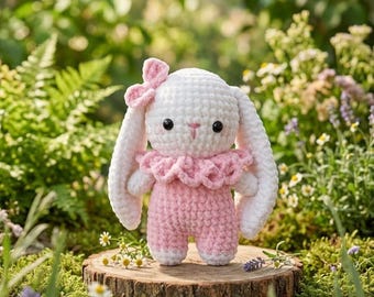 May include: A handmade crochet bunny doll with a white head, long ears, and a pink bow. The bunny wears a pink jumpsuit with a ruffled collar and is posed on a wooden slice, surrounded by greenery and flowers.