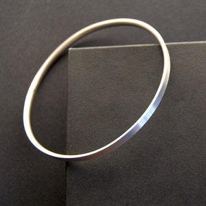 May include: A silver bangle bracelet with a smooth, polished finish. The bracelet is simple and elegant, and would make a great gift.