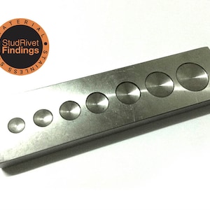 May include: A stainless steel metal tool with seven circular indentations of varying sizes. The tool is rectangular and has a brushed metal finish. The StudRivet Findings logo is in the upper left corner.