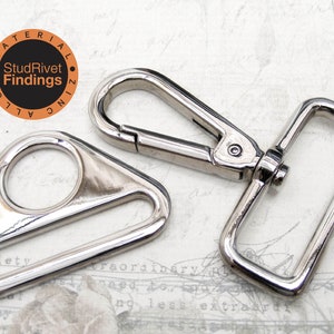 May include: Two silver metal hardware pieces for attaching straps or other accessories. The first piece is a triangular shaped D-ring with a round opening. The second piece is a rectangular swivel hook with a spring-loaded clasp.