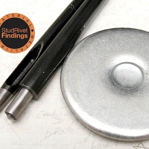 May include: A black metal hand punch tool with a silver metal anvil. The tool has a handle and a punch head with a hole in the center. The anvil is round and has a flat surface. The tool is labeled "Stud Rivet Findings Material Metal".