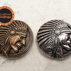 Puede incluir: Dos botones de metal con un diseño de perfil de jefe nativo americano. Los botones son en tonos dorados y plateados. Los botones tienen un diseño en relieve y el año 1913 está grabado en la parte inferior.