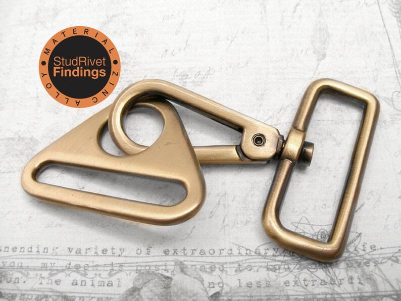 May include: A gold-toned metal triangle swivel hook with a rectangular loop. The hook is attached to a metal D-ring. The hook is made of zinc alloy.