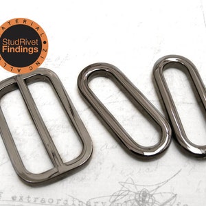 May include: Three metal slider buckles in a gunmetal finish. The buckles are oval shaped with a center bar. The buckles are used for making straps, bags, and other crafts.