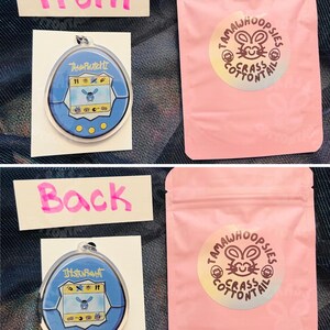 May include: A blue Tamagotchi keychain with a blue and white screen displaying a cartoon character. The keychain is in a clear plastic bag with a pink background. The bag has a sticker on it that says "TamaWhoops!es Grass Cottontail".